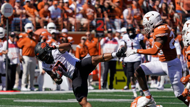 Oct 16, 2021; Austin, Texas, USA; Oklahoma State Cowboys running back Jaylen Warren (7) leaps over Texas Longhorns defensive back Josh Thompson (9) in the second half at Darrell K Royal-Texas Memorial Stadium.
